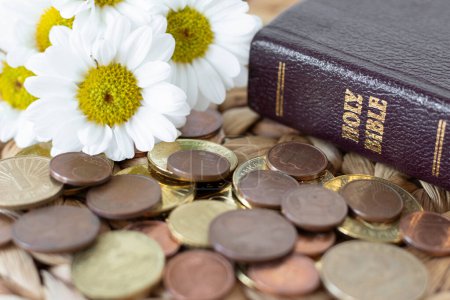 Photo for Coins, flowers, and holy bible book on rustic table. Close-up. Selective focus. Christian tithe, offering, generosity, and church contribution concept. - Royalty Free Image