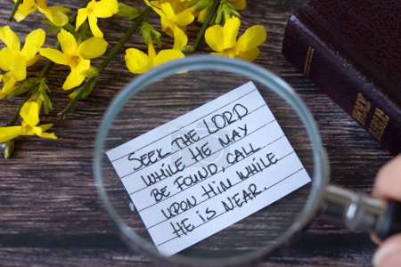 Seek the LORD while He may be found, handwritten quote with magnifying glass and holy bible book. Selective focus. Christian biblical concept of prayer and obedience to God Jesus Christ.