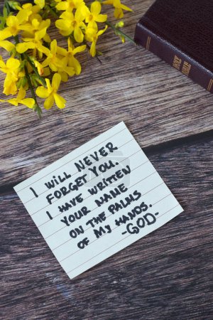 Inspiring handwritten Christian message about God's faithful love, grace, compassion, and promise with flowers and holy bible on wood. Top view. Biblical concept.