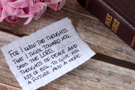 Foto de Inspiring handwritten text about God's future plan, hope, peace, and love for Christians with holy bible book and pink flower. Close-up. Studying biblical prophecy concept. - Imagen libre de derechos
