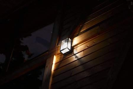 Téléchargez les photos : Street lamp in the evening on a wooden facade. - en image libre de droit
