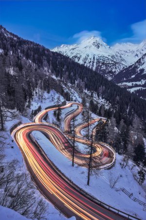 La sinuosa carretera de montaña por la noche con pistas de luz de los coches, Maloja Pass, Suiza
.