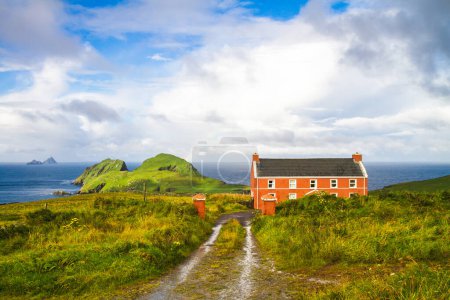 Blick auf das rote Ferienhaus in der St. Finian Bay mit Puffin Island im Hintergrund und Skelligs in der Ferne, County Kerry, Irland. 