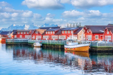 A sailing boat anchored in front of the wooden Rorbu cabins in the Lofoten Islands fishing village, Svolvaer, Lofoten islands, Norway.