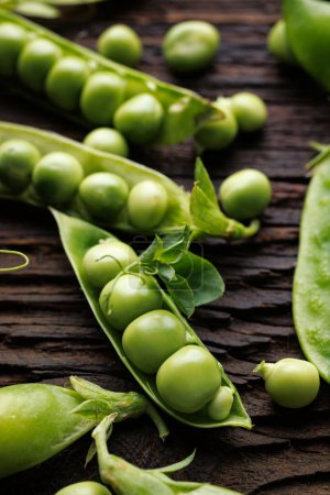 Photo for A pod of green peas on a wooden background, close up view - Royalty Free Image