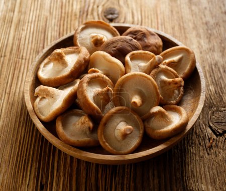 Photo for Fresh shiitake mushrooms on a wooden plate. - Royalty Free Image