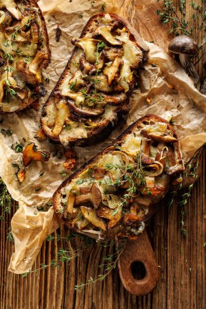 Photo for Grilled sandwiches, toasts with addition of forrest mushrooms Suillus luteus, cheese and thyme herb on parchment paper, close up view - Royalty Free Image