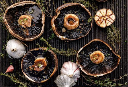 Photo for Grilled portobello mushrooms with thyme and garlic on a cast iron grill plate, close-up - Royalty Free Image