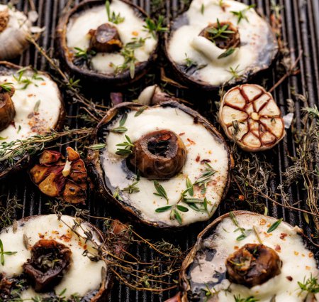 Photo for Grilled portobello mushrooms with melted mozzarella cheese and herbs on a cast iron grill plate, close up view - Royalty Free Image
