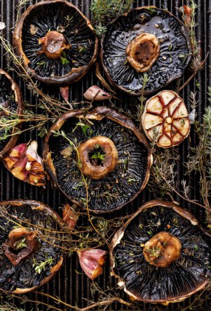 Photo for Grilled portobello mushrooms with thyme and garlic on a cast iron grill plate, close-up, top view - Royalty Free Image