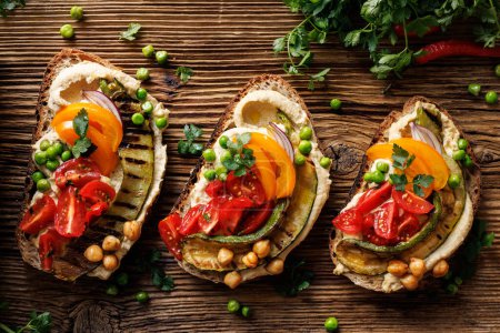Téléchargez les photos : Sandwichs végétariens avec houmous, courgettes grillées et tomates sur une planche rustique, vue sur le dessus. Une nourriture végétarienne saine et délicieuse - en image libre de droit