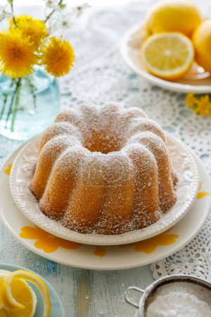Photo for Lemon bundt cake (Babka) sprinkled with powdered sugar served on a plate, close up view - Royalty Free Image