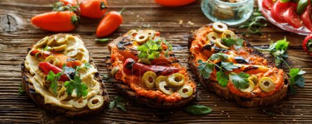 Photo for Sandwiches from toasted traditional sourdough bread with hummus, grilled peppers and green olives  sprinkled with fresh parsley on a wooden board, close up view - Royalty Free Image
