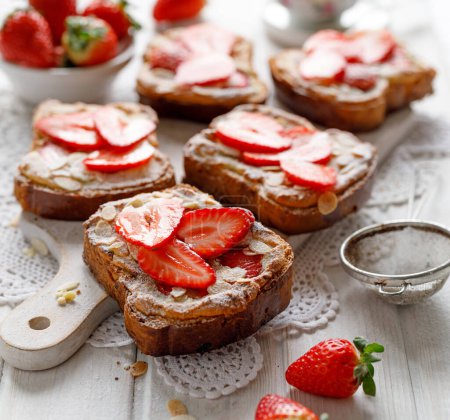 Téléchargez les photos : Bostock une pâtisserie française faite de brioche tranchée avec de la crème de frangipane et des fraises fraîches servies sur un tableau blanc, vue de près. Délicieux petit déjeuner ou dessert - en image libre de droit