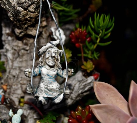 Téléchargez les photos : Petite sorcière chevauchant sur une balançoire décorant un environnement de jardin - en image libre de droit