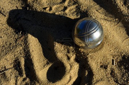 Foto de Una sola bola de metal de Boules en la arena con una larga sombra del sol de la tarde - Imagen libre de derechos