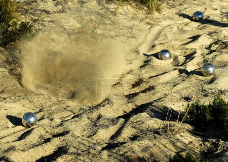 Foto de Una bola de metal de Boules desapareciendo dramáticamente en un spray de arena - Imagen libre de derechos
