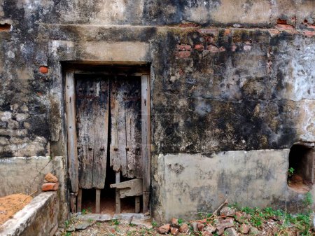 Téléchargez les photos : Porte en bois cassée La porte en bois usée sur un mur de briques rouges endommagé Une porte en bois cassée au milieu de murs endommagés - en image libre de droit