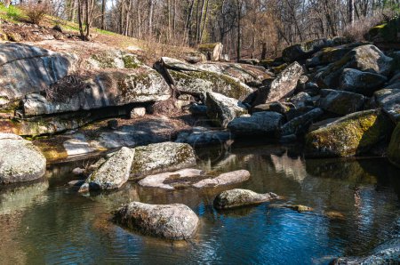 Photo for Ukraine. Early spring in Sofievsky park in Uman. A lake in the park, surrounded by a heap of stones. The stones are covered with moss. Copy space. - Royalty Free Image