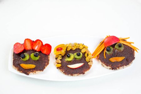 Téléchargez les photos : Drôle de toasts visages au chocolat tartiné et dattes et fruits - en image libre de droit