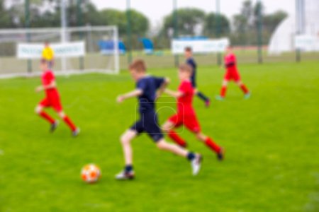 Photo for Blur of young kids playing a youth soccer match outdoors on an green soccer pitch. - Royalty Free Image