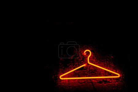 Téléchargez les photos : Cintre néon signe lumineux. Lumière rouge néon sous la forme d'un cintre sur fond noir - en image libre de droit