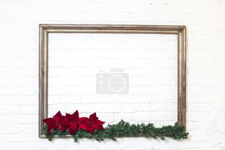 Téléchargez les photos : Cadre photo en bois avec une branche de pin et fleur rouge sur fond de brique blanche - en image libre de droit