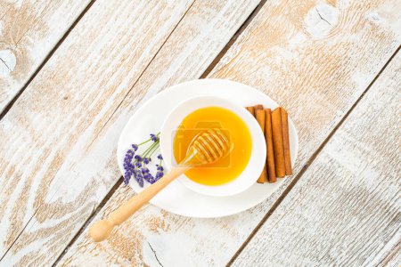 Photo for Organic honey decorated with dry lavender flowers and cinnamon on a wooden background - Royalty Free Image