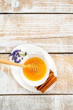 Photo for Organic honey decorated with dry lavender flowers and cinnamon on a wooden background - Royalty Free Image