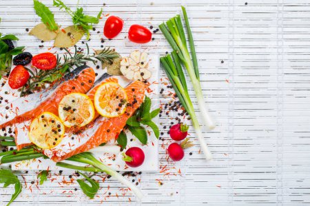 Foto de Filete de salmón crudo, especias y verduras en un plato blanco. Vista superior
. - Imagen libre de derechos