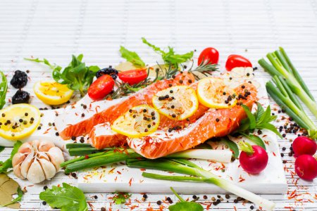 Foto de Filete de salmón crudo, especias y verduras en un plato blanco. Vista superior
. - Imagen libre de derechos