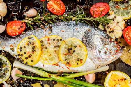 Photo for Delicious fresh bream or dorade fish on dark background. Fish with aromatic herbs, lemon, garlic, spices and vegetables - healthy food, diet or cooking concept - Royalty Free Image