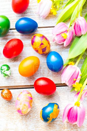 Foto de Coloridos huevos de Pascua con flores sobre fondo de madera - Imagen libre de derechos