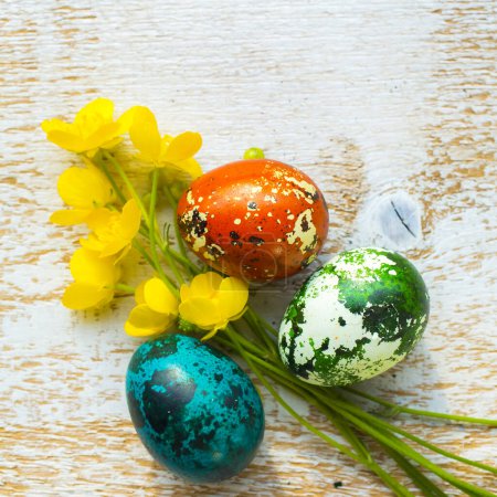 Téléchargez les photos : Oeufs de Pâques colorés avec des fleurs sur fond en bois - en image libre de droit