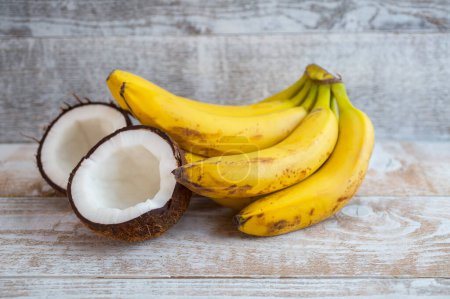 Téléchargez les photos : Noix de coco et bananes sur fond bois - en image libre de droit