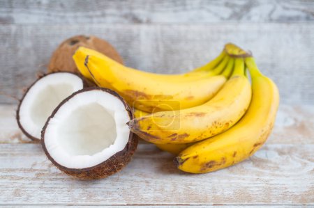 Téléchargez les photos : Noix de coco et bananes sur fond bois - en image libre de droit