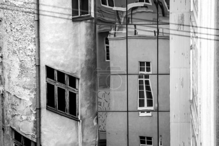 Téléchargez les photos : Reflet de façade en pierre sur la façade en verre moderne. noir et blanc photo - en image libre de droit