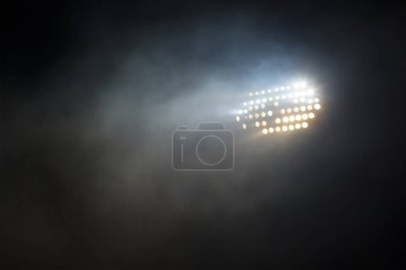 Light tower lit at a stadium during nightime.