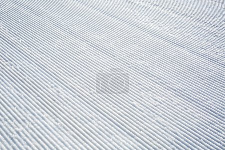 Téléchargez les photos : Pistes de dameuse fraîche sur une piste de ski de montagne - en image libre de droit