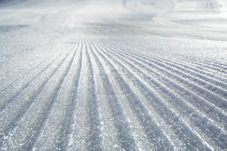 Téléchargez les photos : Pistes de dameuse fraîche sur une piste de ski de montagne - en image libre de droit