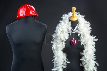 Foto de Macho con casco de construcción rojo y hembra con plantilla de torso de maniquí boa blanco sobre fondo negro - Imagen libre de derechos