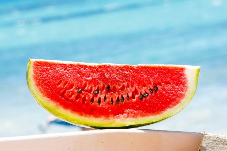 Photo for Juicy slice of watermelon against natural background on the beach - Royalty Free Image