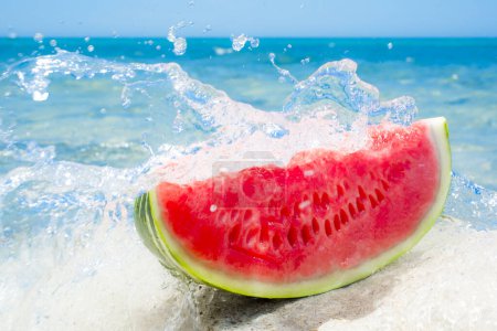 Photo for Slice of watermelon on the seashore and a wave breaking - Royalty Free Image