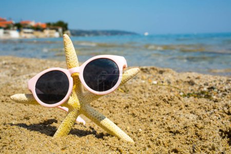 Photo for Funny starfish with sunglass on the sandy beach at sea background - Royalty Free Image