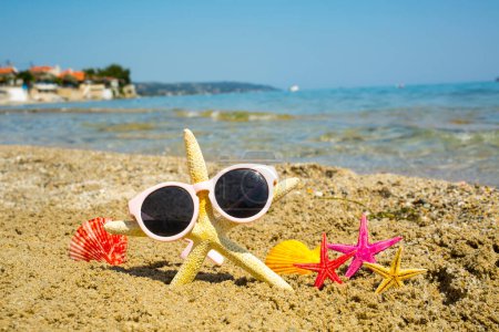 Téléchargez les photos : Étoile de mer drôle avec verre de soleil sur la plage de sable en fond de mer - en image libre de droit