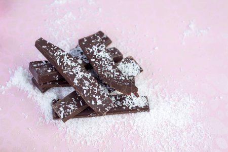 Téléchargez les photos : Tranches de chocolat avec poudre sur fond rose - en image libre de droit