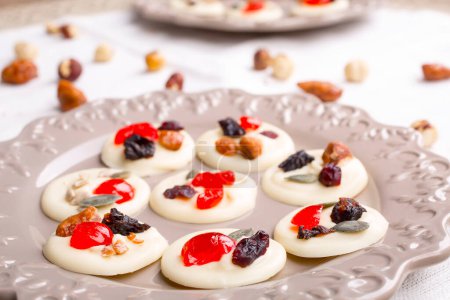 Téléchargez les photos : Gâteaux au chocolat blanc aux fruits confits, noix et graines sur table en bois - en image libre de droit