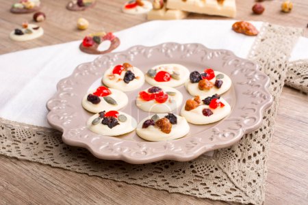 Foto de Pastel de chocolate blanco con fruta confitada, nueces y semillas en mesa de madera - Imagen libre de derechos