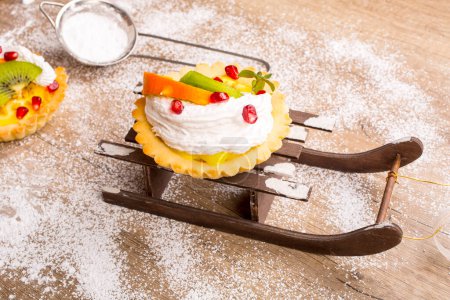 Photo for Sweet cake with fruits on the Christmas arrangement with sleds and snow - Royalty Free Image
