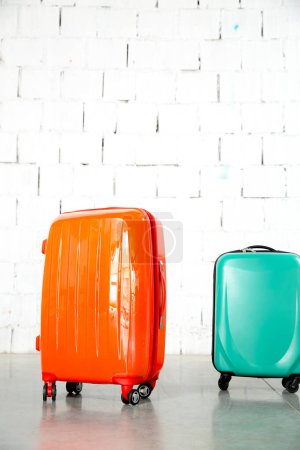 Photo for Orange and green travel bags on white brick background - Royalty Free Image